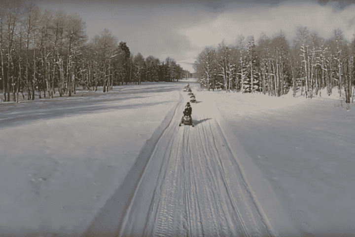 a snow covered road with snowmobilers