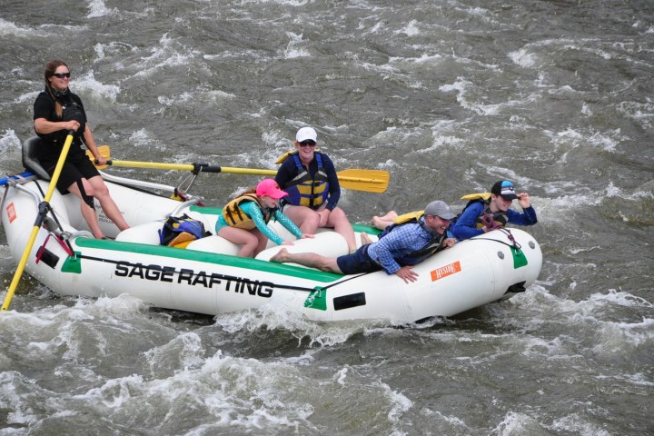 a group of people riding on the back of a boat in the water