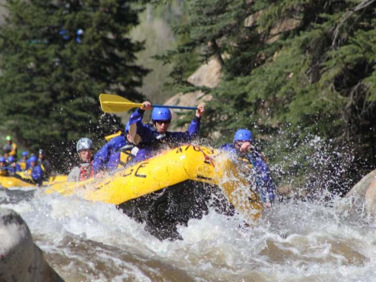 a man flying through the air while riding a snowboard down a river