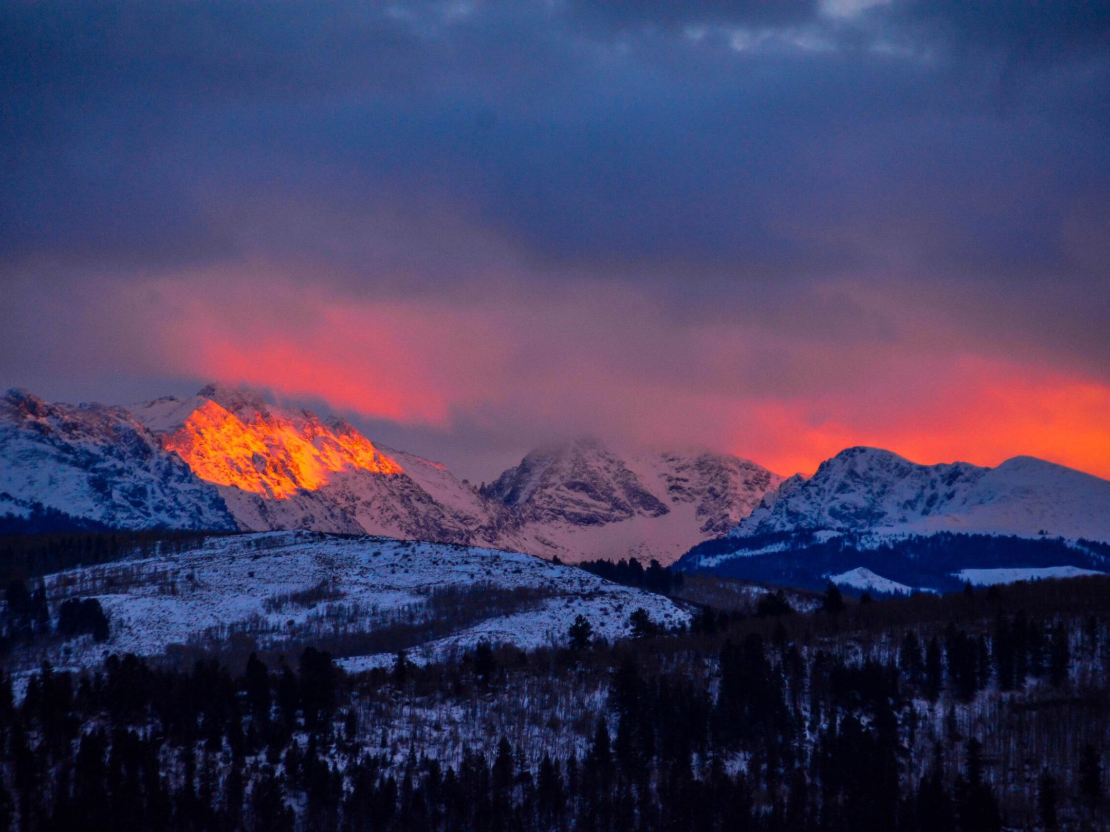 a sunset over a snow covered mountain