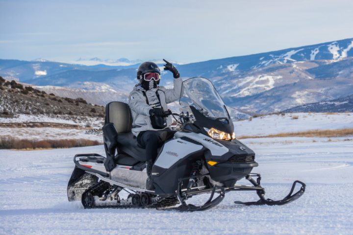 a man riding a motorcycle down a snow covered mountain