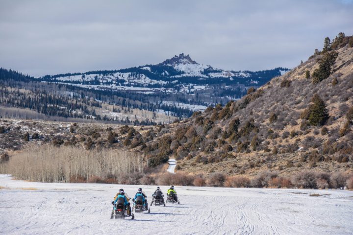 a group of people riding on top of a snow covered mountain