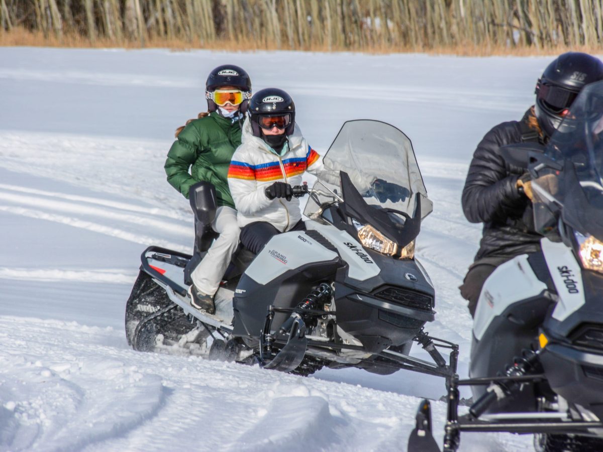 a group of people riding skis across snow covered ground