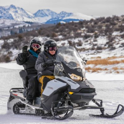 a man riding a motorcycle down a snow covered mountain