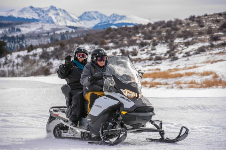 a man riding a motorcycle down a snow covered mountain