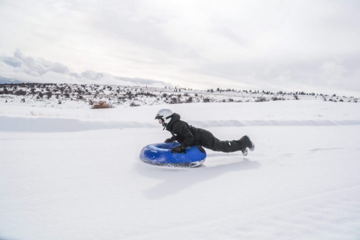 a person riding a snowboard down a snow covered slope