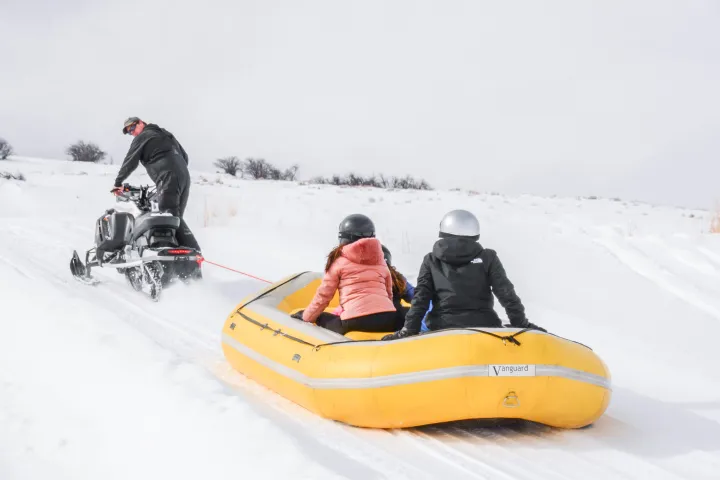 A tour guide takes people up to the top of a tubing run as they sit inside the tube and get hauled to the top.