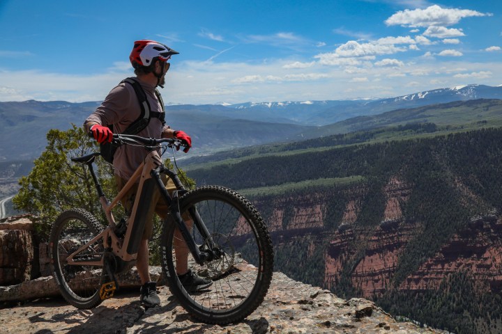a man riding a bicycle with a mountain in the background