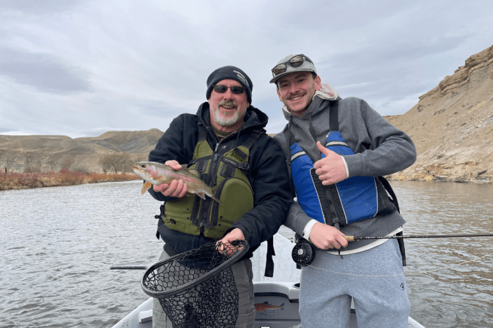 a man sitting next to a body of water